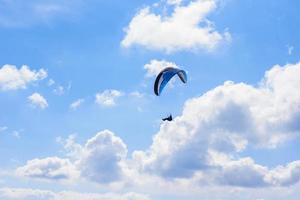 hombre en un paracaídas volando en el cielo despejado foto