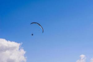 hombre en un paracaídas volando en el cielo despejado foto