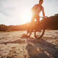 ciclista montando a lo largo de la playa al atardecer foto