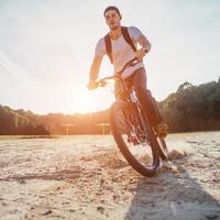 ciclista montando a lo largo de la playa al atardecer foto