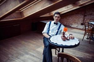 Elegant young man in suspenders and glasses in cafe photo