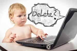 little girl is sitting at table with her black laptop photo