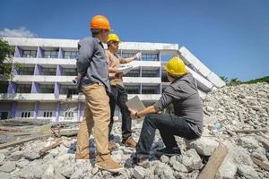 Engineer team and worker checking blueprint for emolition construction plan and inspect at the site. photo