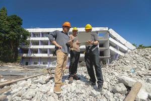 equipo de ingenieros y trabajadores revisando el plano para el plan de construcción de demolición e inspeccionando en el sitio. foto