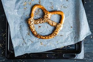 pretzels suaves caseros recién preparados. diferentes tipos de panecillos horneados con semillas sobre un fondo negro. foto