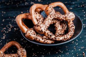 Fresh prepared homemade soft pretzels. Different types of baked bagels with seeds on a black background. photo