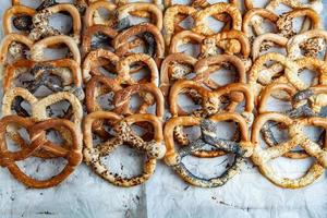 Fresh prepared homemade soft pretzels. Different types of baked bagels with seeds on a black background. photo
