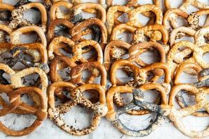 Fresh prepared homemade soft pretzels. Different types of baked bagels with seeds on a black background. photo