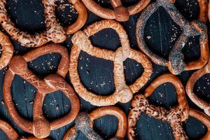 Fresh prepared homemade soft pretzels. Different types of baked bagels with seeds on a black background. photo