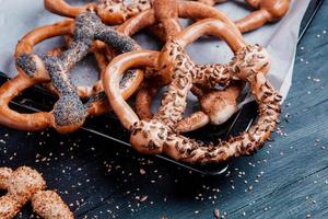 Fresh prepared homemade soft pretzels. Different types of baked bagels with seeds on a black background. photo