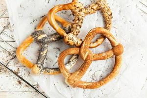 Fresh prepared homemade soft pretzels. Different types of baked bagels with seeds on a black background. photo