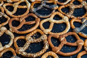 Fresh prepared homemade soft pretzels. Different types of baked bagels with seeds on a black background. photo