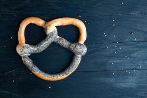 Fresh prepared homemade soft pretzels. Different types of baked bagels with seeds on a black background. photo