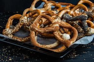 Fresh prepared homemade soft pretzels. Different types of baked bagels with seeds on a black background. photo