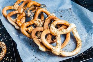 Fresh prepared homemade soft pretzels. Different types of baked bagels with seeds on a black background. photo