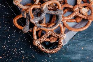 Fresh prepared homemade soft pretzels. Different types of baked bagels with seeds on a black background. photo