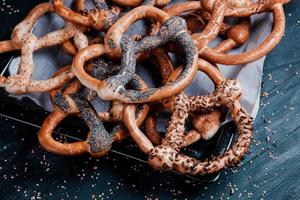 Fresh prepared homemade soft pretzels. Different types of baked bagels with seeds on a black background. photo