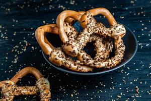 Fresh prepared homemade soft pretzels. Different types of baked bagels with seeds on a black background. photo