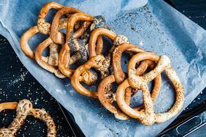 Fresh prepared homemade soft pretzels. Different types of baked bagels with seeds on a black background. photo