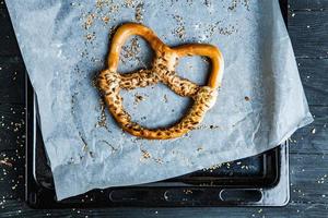 pretzels suaves caseros recién preparados. diferentes tipos de panecillos horneados con semillas sobre un fondo negro. foto