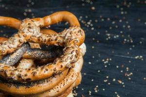 Fresh prepared homemade soft pretzels. Different types of baked bagels with seeds on a black background. photo
