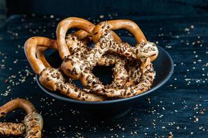 Fresh prepared homemade soft pretzels. Different types of baked bagels with seeds on a black background. photo