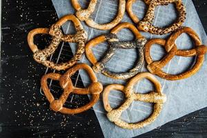 Fresh prepared homemade soft pretzels. Different types of baked bagels with seeds on a black background. photo