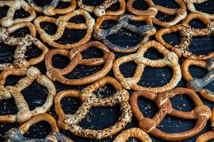 Fresh prepared homemade soft pretzels. Different types of baked bagels with seeds on a black background. photo