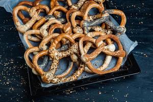 Fresh prepared homemade soft pretzels. Different types of baked bagels with seeds on a black background. photo