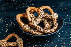Fresh prepared homemade soft pretzels. Different types of baked bagels with seeds on a black background. photo