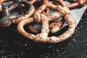 Fresh prepared homemade soft pretzels. Different types of baked bagels with seeds on a black background. photo