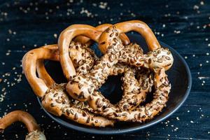 Fresh prepared homemade soft pretzels. Different types of baked bagels with seeds on a black background. photo