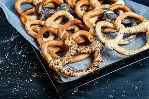 Fresh prepared homemade soft pretzels. Different types of baked bagels with seeds on a black background. photo