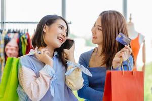 Asian girls enjoy shopping with cashless credit card phone calling loan from callcenter payment with friend happy moment fun in sale shop together.