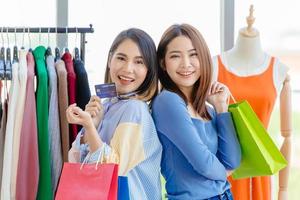 Asian girls enjoy shopping with cashless credit card payment with friend happy moment fun in sale shop together. photo