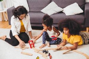 Mother parent playing with children learning to solve puzzle toy at home apartment. Nanny looking or childcare at living room black people.