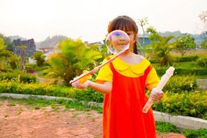 Lovely Baby girl wears yellow-orange outfit, gokowa outfit or Mugunghwa playing bubble in a public park. Girls and teen fashion dress. photo