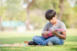 A half-Thai-Indian boy relaxes by learning to play ukulele strings while learning outside of school in a park photo