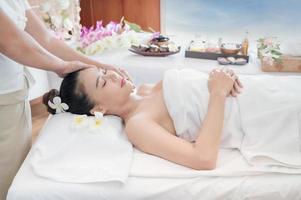 una hermosa mujer asiática está cómodamente relajada y duerme en una tienda de spa después de que la masajista haya masajeado su cuerpo foto