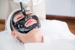 masajistas profesionales en salones de spa usan cepillos de barro de spa para dar tratamientos faciales a bellezas asiáticas foto