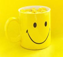 Happy yellow cup with cornflakes on bright yellow background. photo