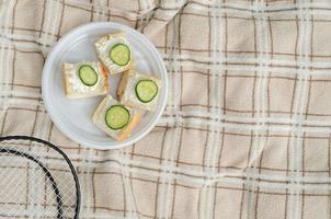 raquetas de bádminton y sándwiches de verano para picnic deportivo familiar de verano, vista superior. foto