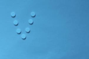 la letra v en forma de pastillas sobre fondo azul clásico. foto