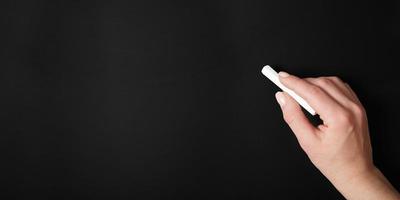 female hand against blank chalk board background photo