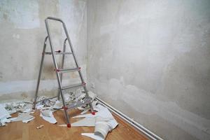 empty room with bare walls ladder and old wallpaper scraps on floor during redecoration wth copy space photo