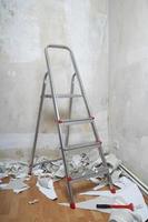 habitación vacía con escaleras de paredes desnudas y viejos restos de papel pintado en el suelo durante la redecoración foto