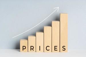 Increasing or Rising prices concept. Wooden block bar chart graph with text and upward trend line drawn on background. Copy space photo