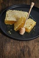 Honeycomb and honey dipper on wooden table photo