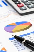 Marketing report chart and graph analysis with pen and calculator photo