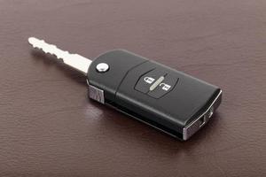 Modern remote car key on brown leather background photo